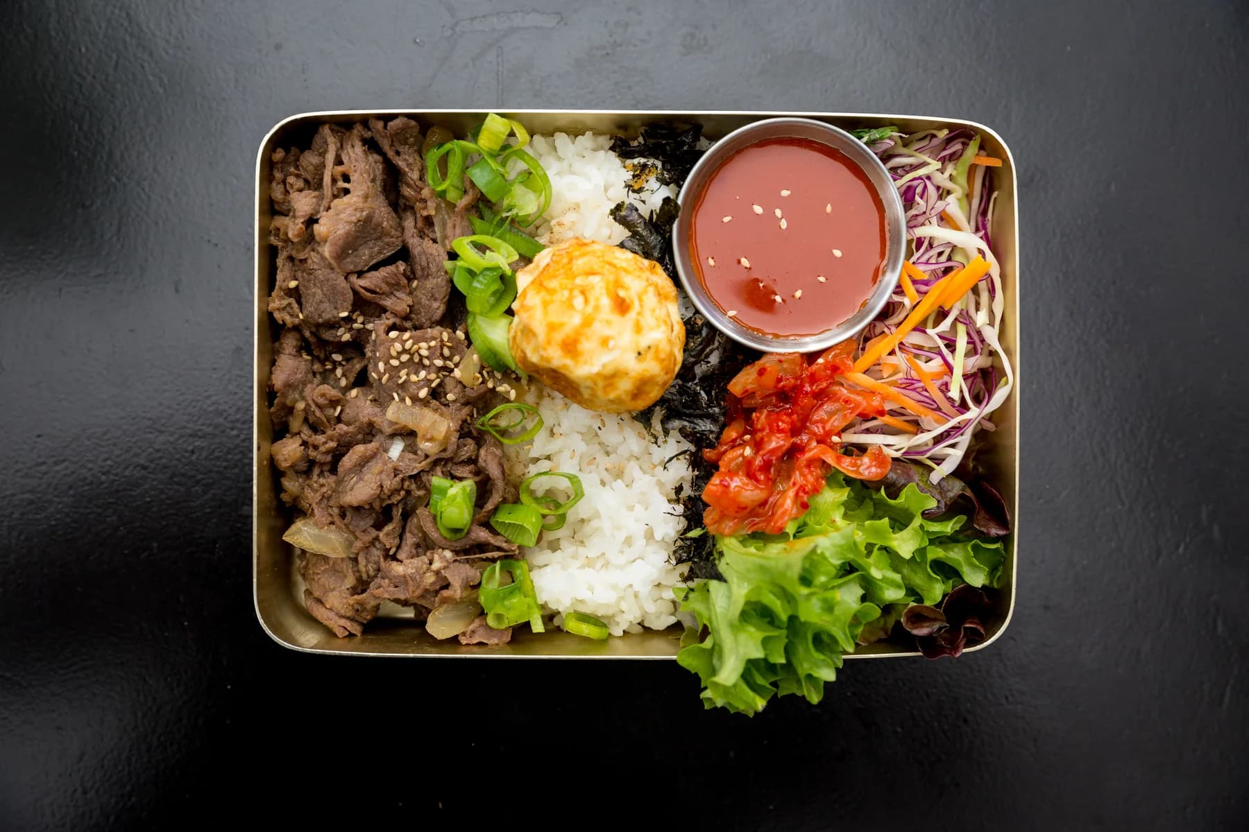 Korean rice box with beef, vegetables and fried egg
